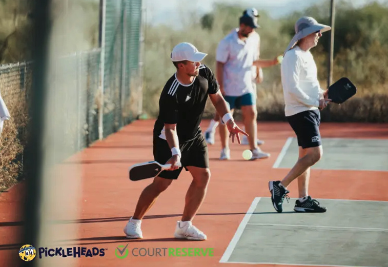 Pickleball players hitting the ball. Text overlay of Pickleheads and CourtReserve logos