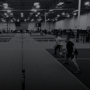 Club Pickleball USA Indoor pickleball game with players in action, large american flag on wall