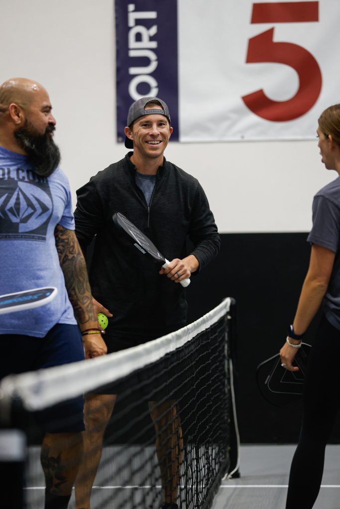 00A9415-683x1024 People playing pickleball indoors near net