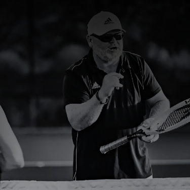 Bill Riddle Man teaching tennis while holding a racket