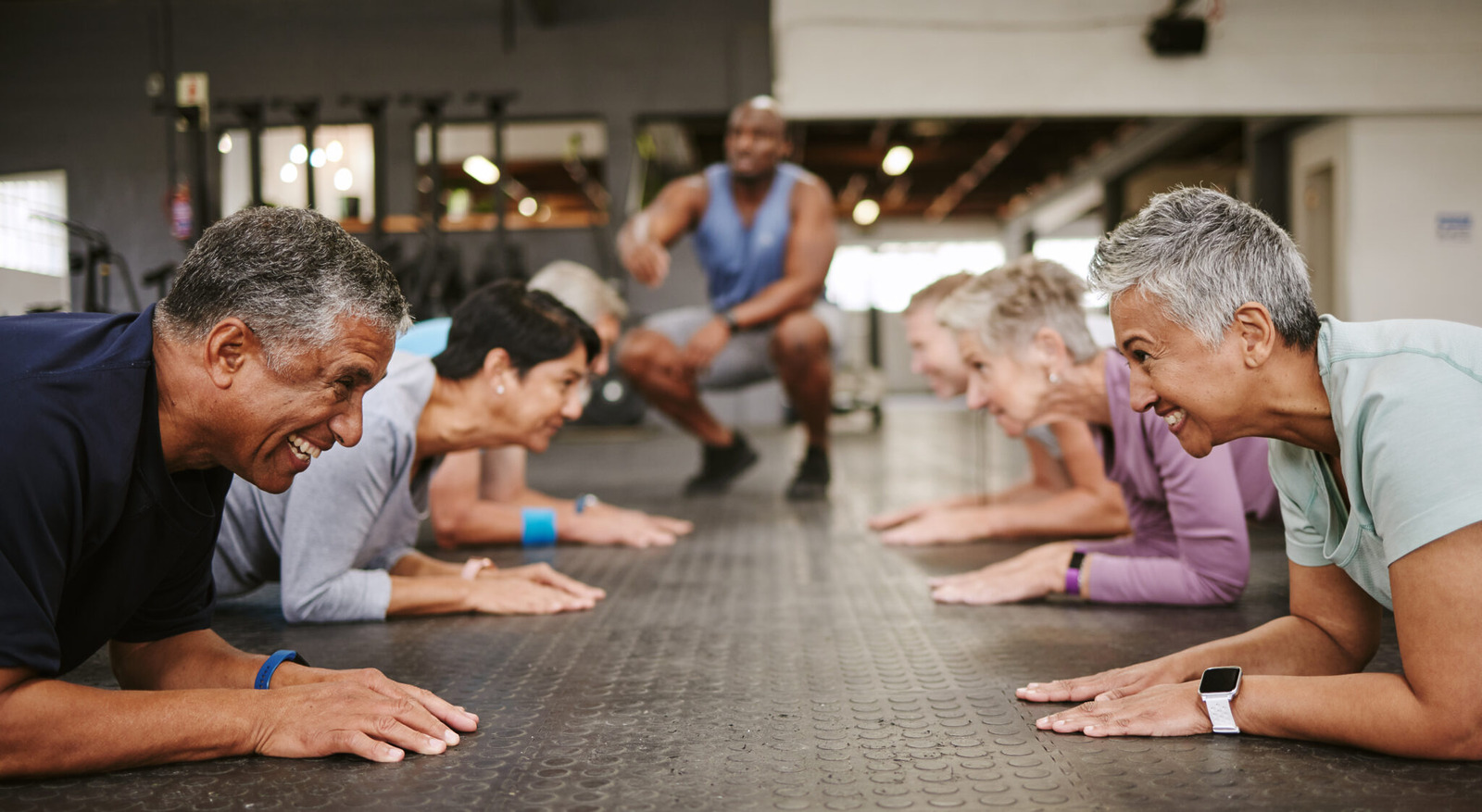 A group of older adults engaging in a plank exercise at a gym, smiling and encouraging one another. The image conveys energy, wellness, and community—key themes of UnitedHealthcare’s Renew Active program for senior fitness and mental well-being.