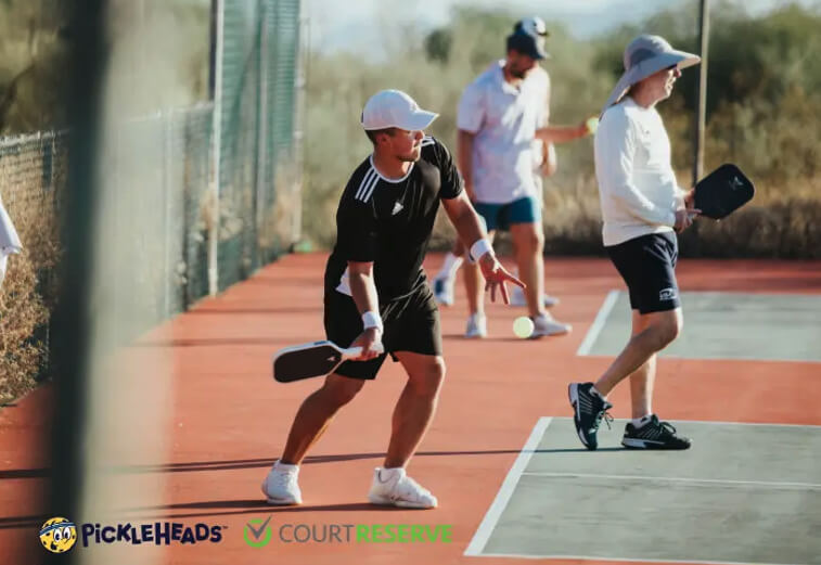 Pickleball players hitting the ball. Text overlay of Pickleheads and CourtReserve logos 