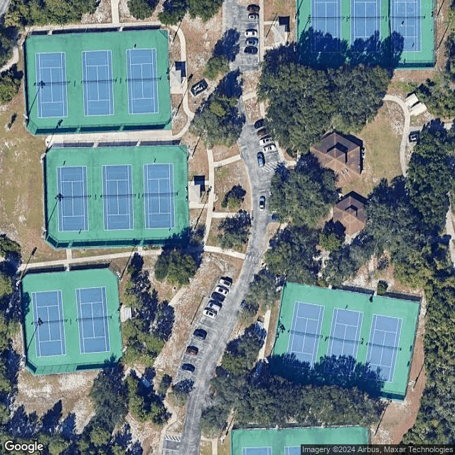 Aerial view of six tennis courts with nearby parking and trees
