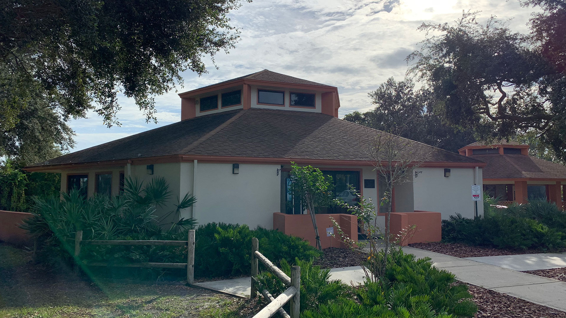Octagonal building with a wooden fence and lush greenery