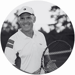 Smiling man in tennis attire holding a racket