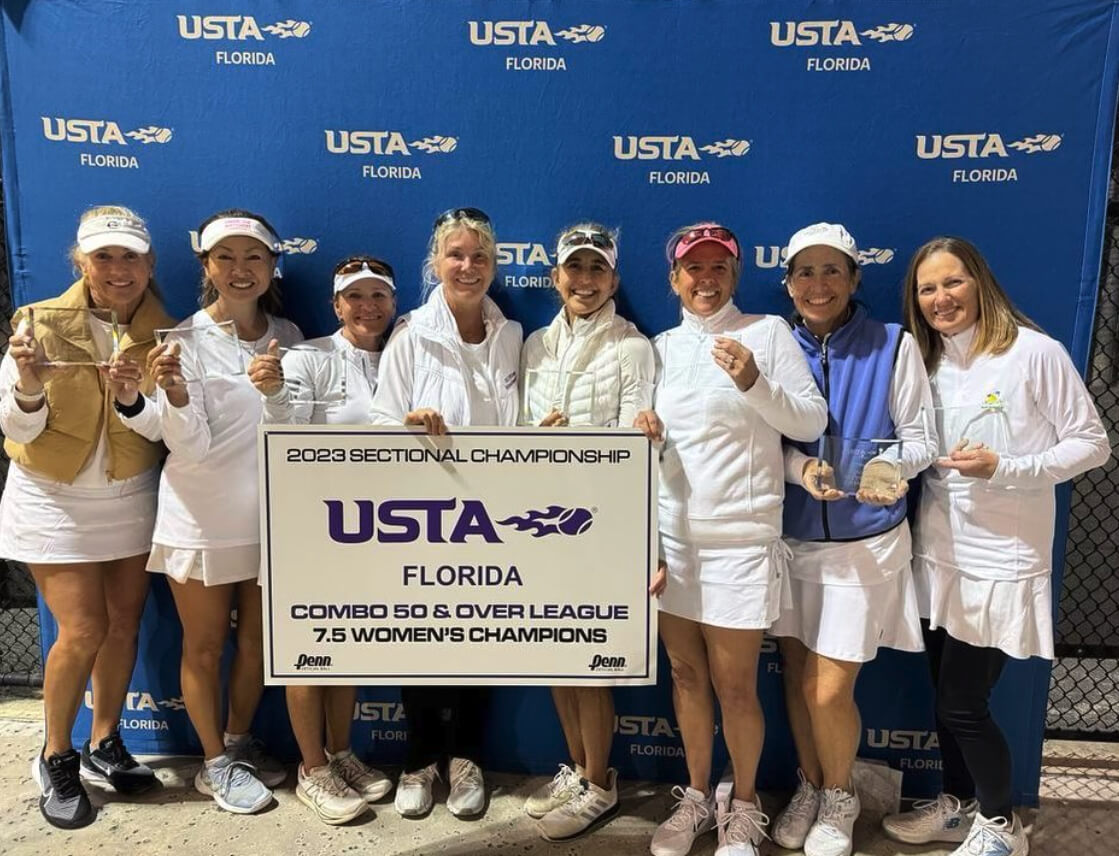 Women's tennis team holding a championship sign and trophies against USTA Florida backdrop