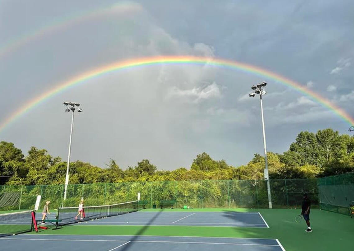 Rainbow over an outdoor tennis court with players