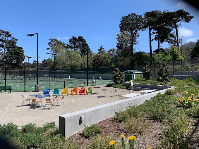 Patio with colorful chairs overlooking tennis courts at a community facility.