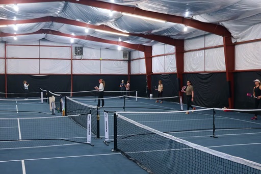 Players warming up across multiple indoor pickleball courts at Bozeman Classic Pickleball Club in Bozeman, Montana.