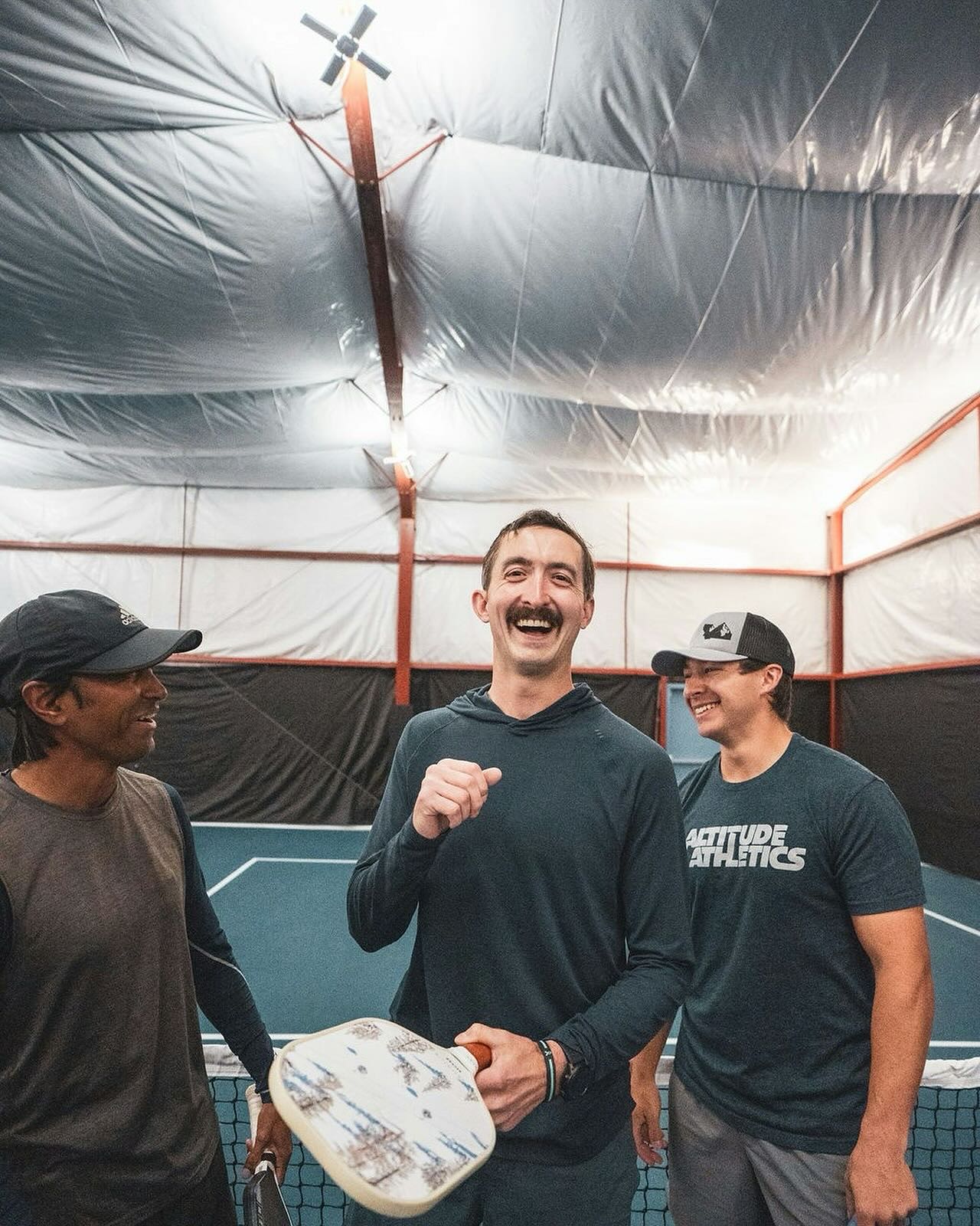 Three players share a laugh after a game on the indoor courts at Bozeman Classic Pickleball Club.