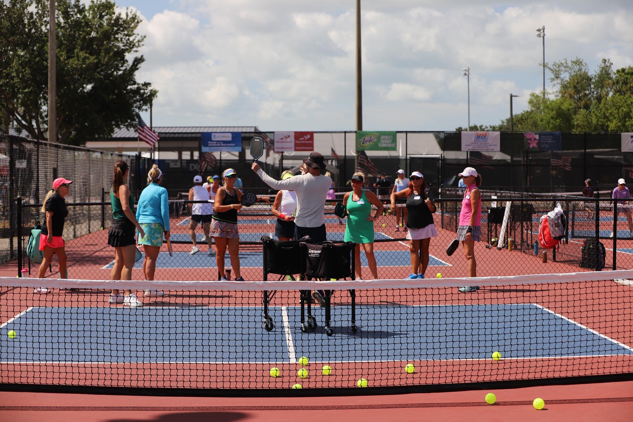 Pickleball clinic with instructor and group on outdoor courts.