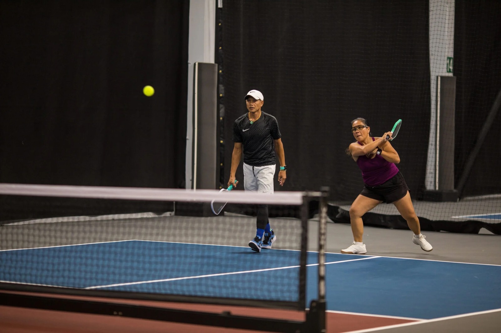 Two players competing in a doubles match on an indoor pickleball court at Rally Pickleball Club in Auburn, Washington.