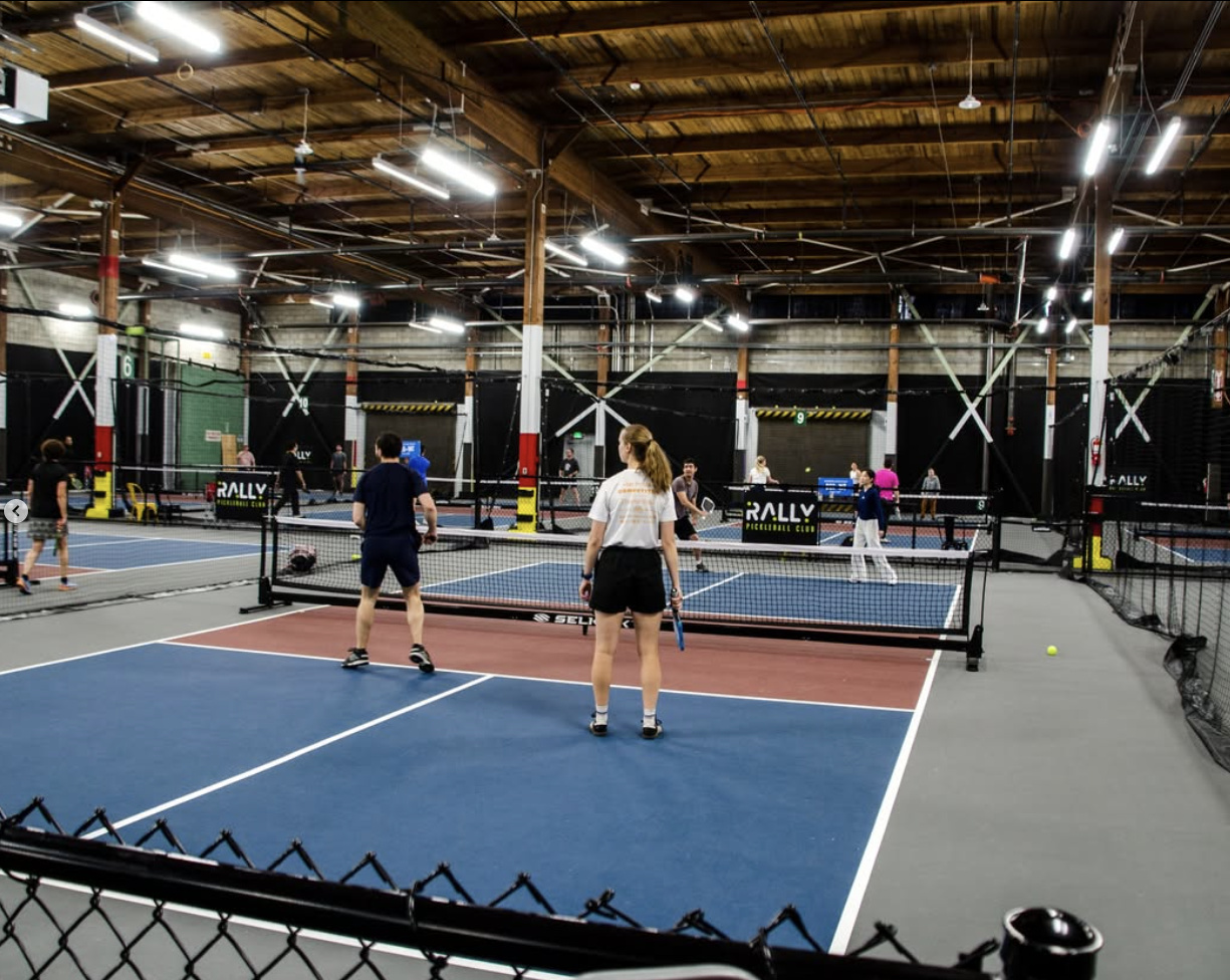 An overhead view of multiple indoor pickleball courts in use at Rally Pickleball Club in Auburn, Washington, with Rally branding visible on the court dividers.