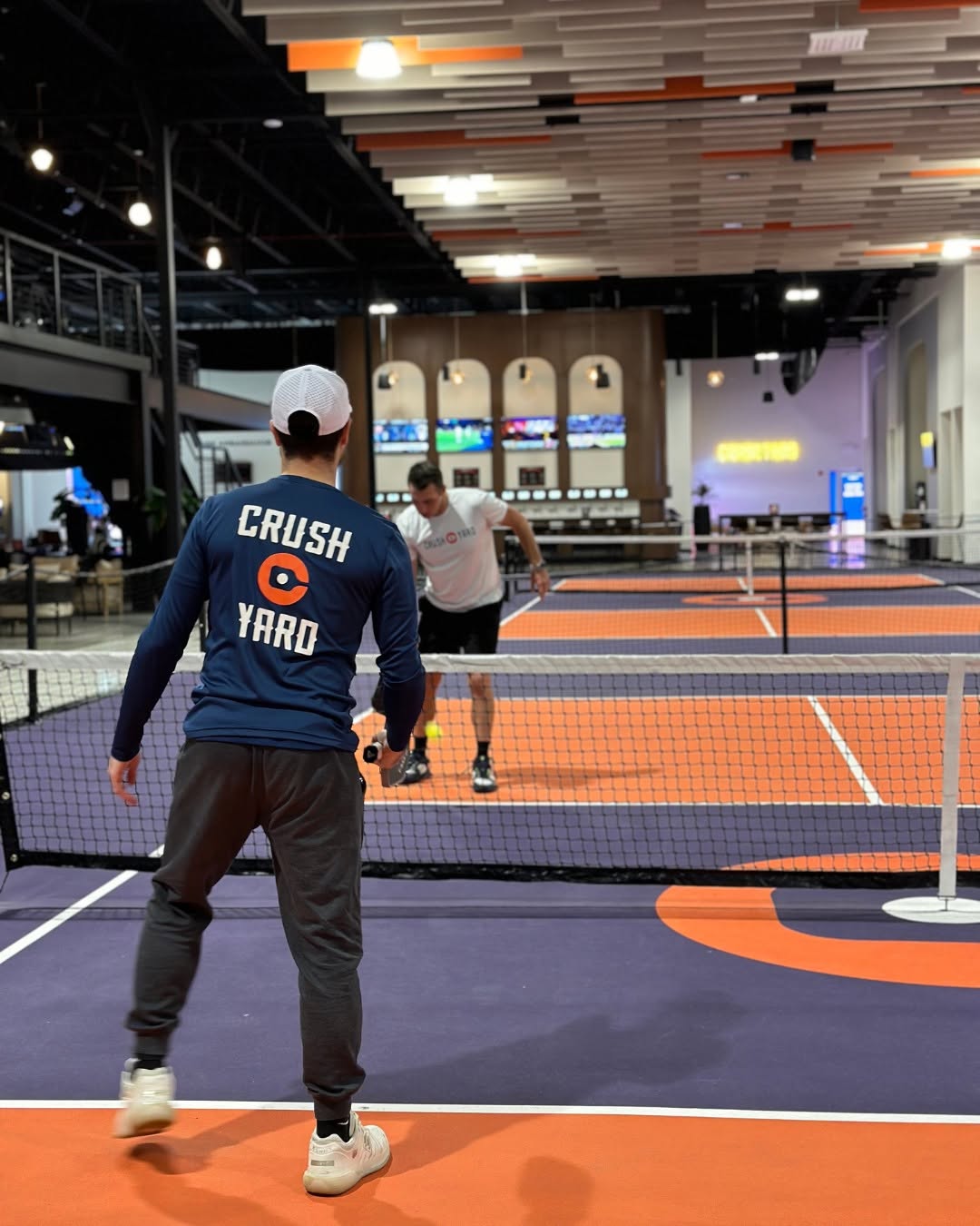 Players competing on an indoor pickleball court at Crush Yard