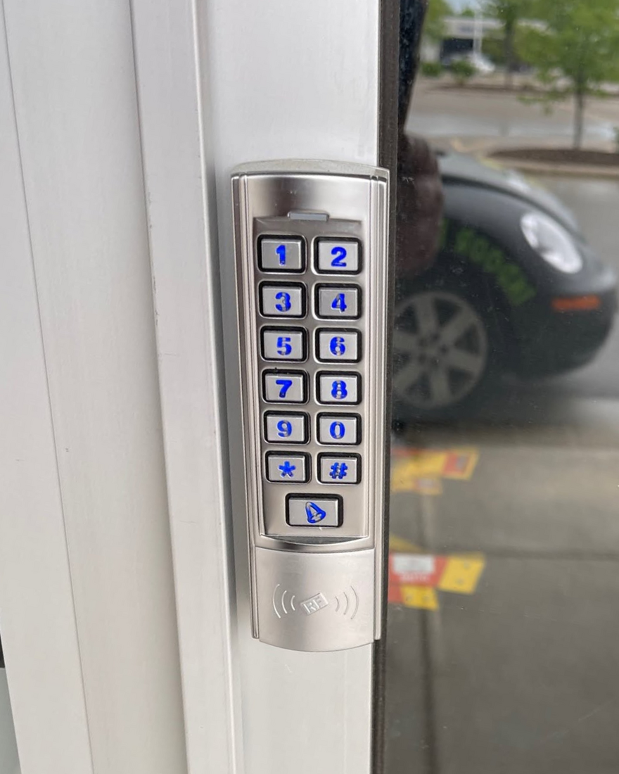 An illuminated keypad on the glass entrance door at Pickle Pro Courts, where players enter with their booking PIN.